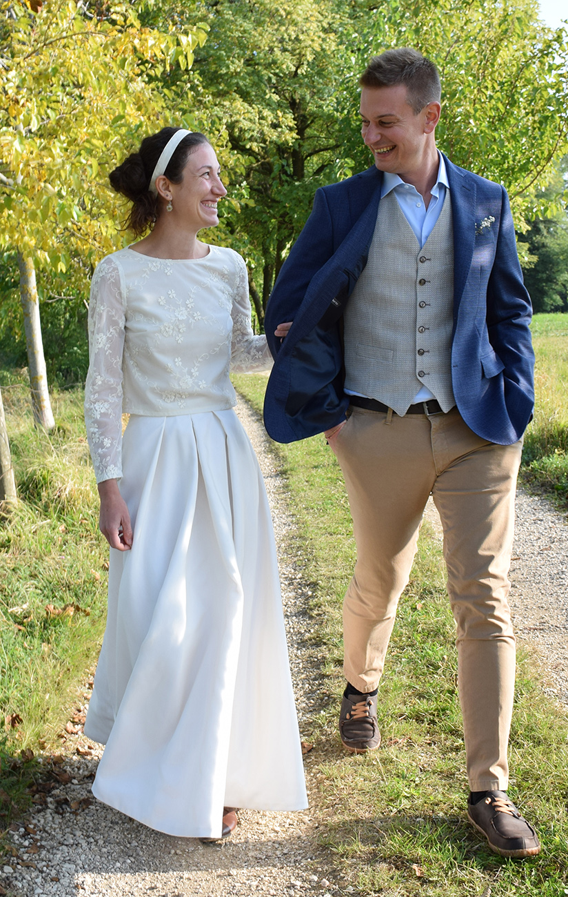 Coppia elegante cammina su sentiero tra gli alberi.