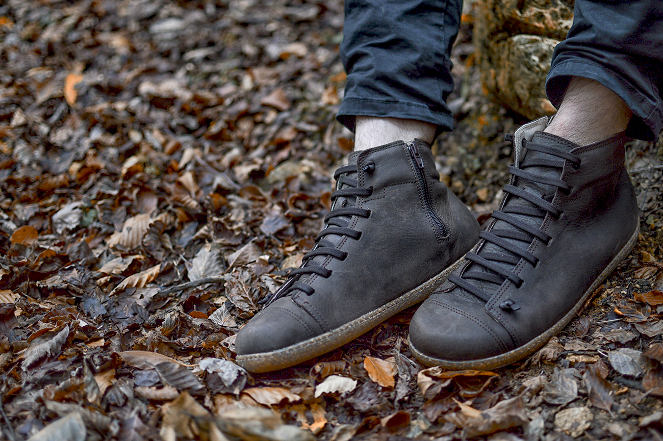 Scarpe alte nere tra foglie secche in autunno.