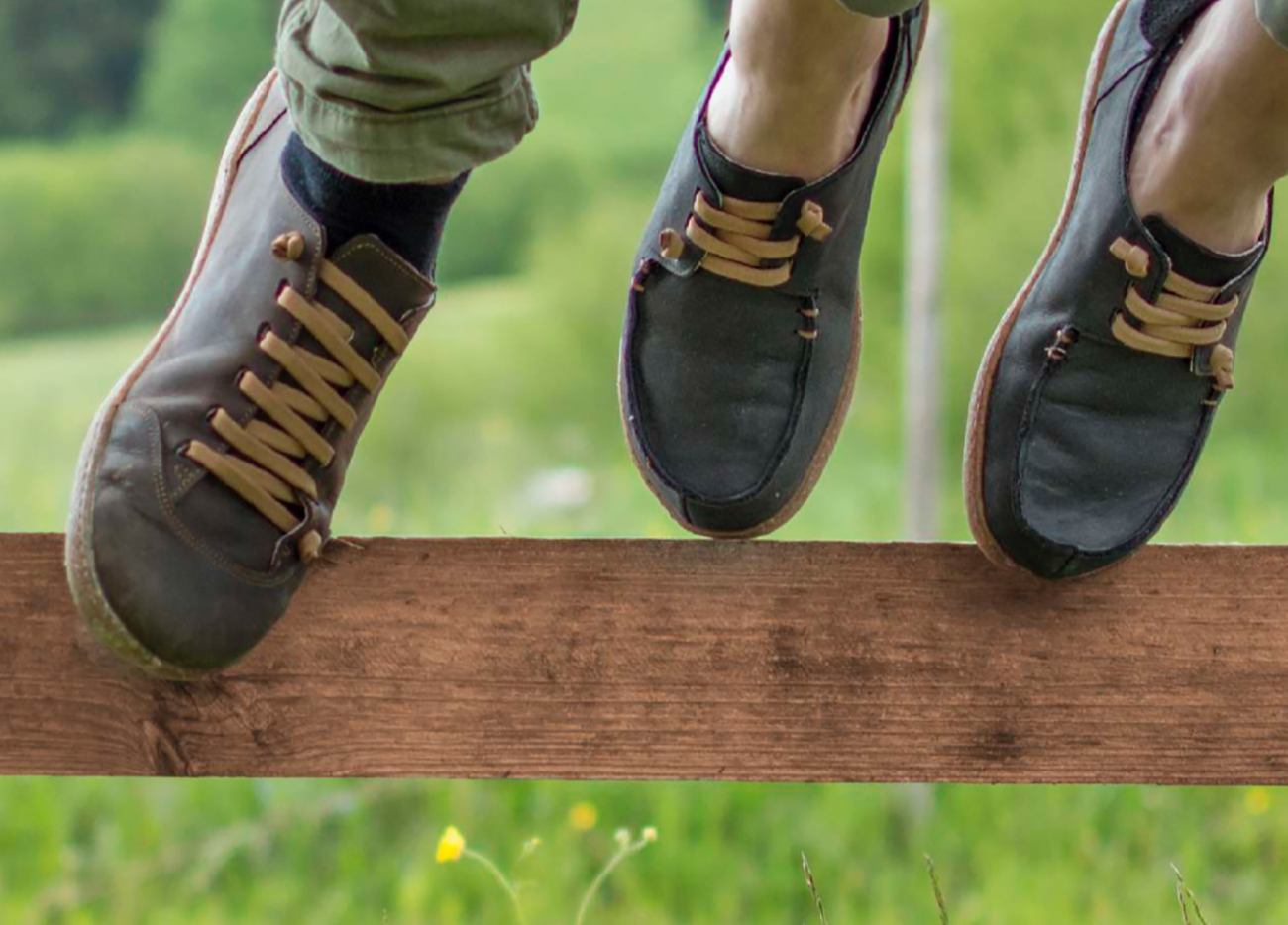 Scarpe sportive con lacci beige su una staccionata di legno.