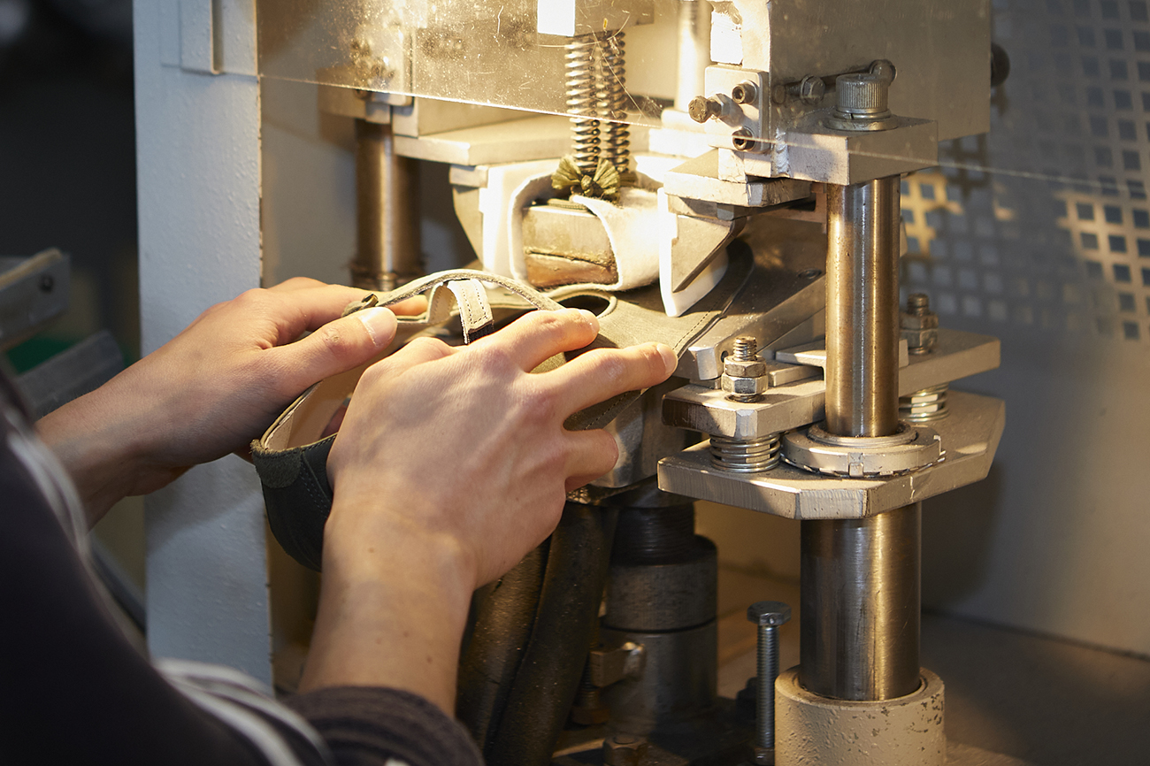 Mani lavorano una scarpa su macchina artigianale per calzature.