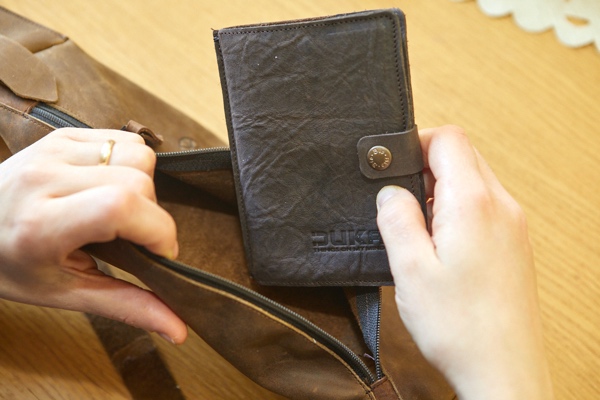 Portafoglio in pelle marrone che viene riposto in borsa.
