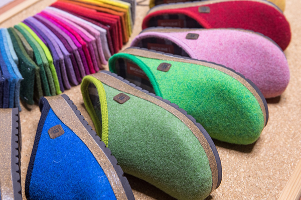 Colorata esposizione di pantofole in feltro su piano in sughero.