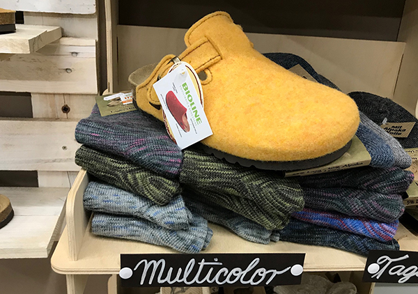 Sabot giallo Bioline su pila di calzini multicolore, cartello multicolor.