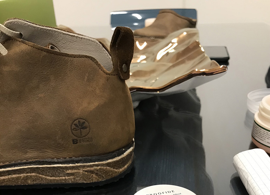 Scarpa in cuoio marrone con logo inciso su sfondo nero