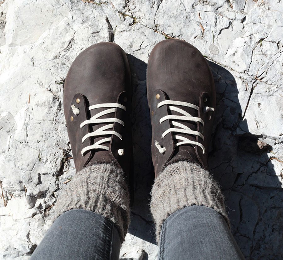 Scarpe da trekking marroni con calzini grigi su roccia chiara.