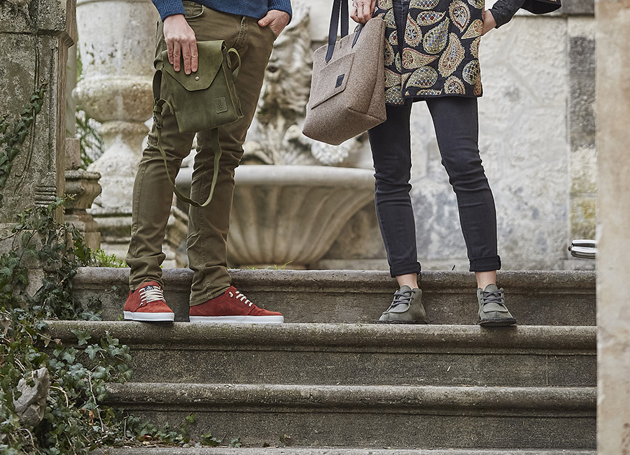 Due persone con sneakers e borse in feltro su scalini in pietra antica.