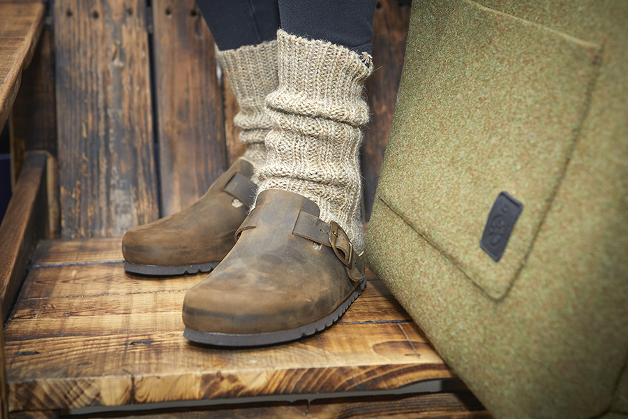 Scarpe marroni Bioline con calzini beige su gradino in legno.