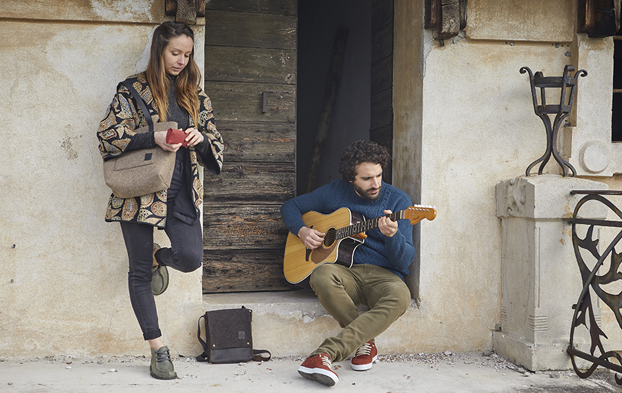 Donna in piedi accanto a uomo seduto che suona chitarra.