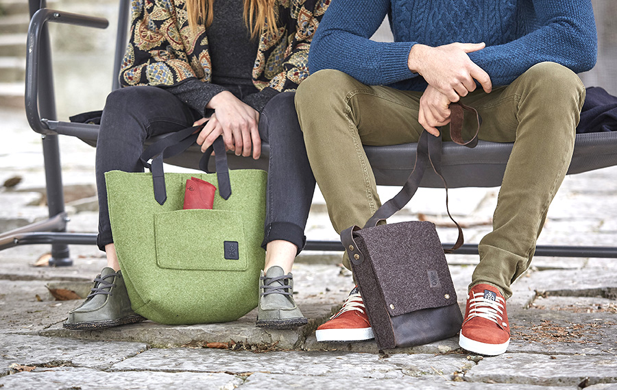 Due persone sedute su panchina con scarpe Bioline e borse in feltro.