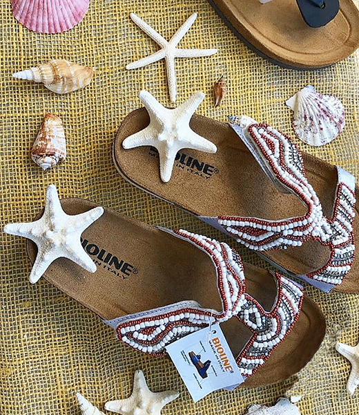 Sandali decorati con perline e stelle marine su fondo giallo