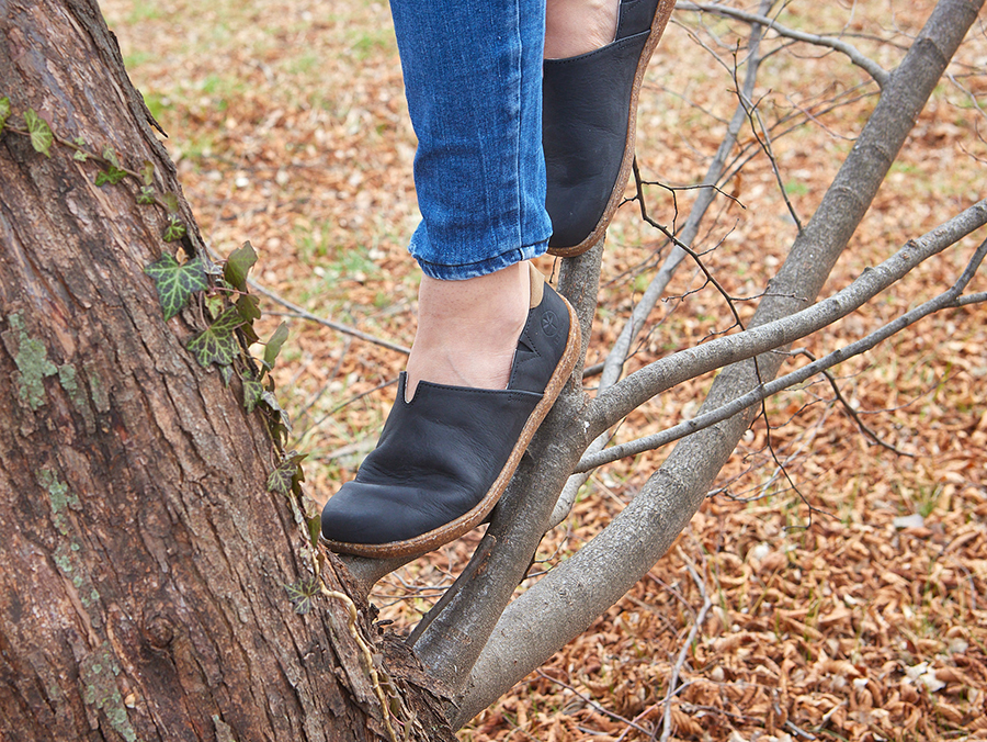 Scarpe nere Bioline indossate su albero in ambiente naturale.