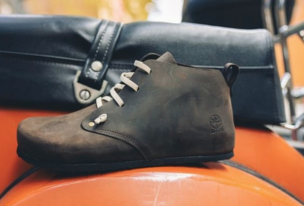 Scarpa stringata Bioline marrone su sella arancione con borsa nera.