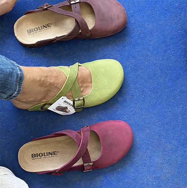 Sabot Bioline colorati indossati su moquette blu con etichetta.