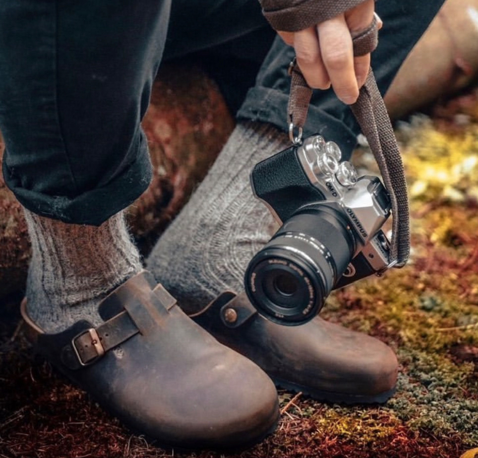 Sabot Bioline marroni con calzini grigi e macchina fotografica.