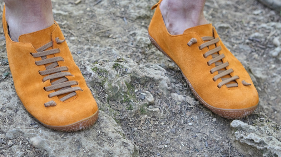 Scarpe arancioni Bioline con lacci su terreno roccioso.